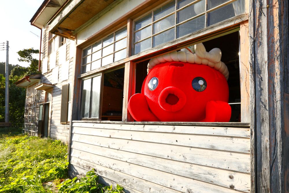 El Taller YES, que se encuentra en la antigua Escuela Secundaria de Iriya, una construcción de madera, y Octopus-kun. (Imagen de la asociación para la revitalización Minamisanriku Fukkō Dako no Kai)