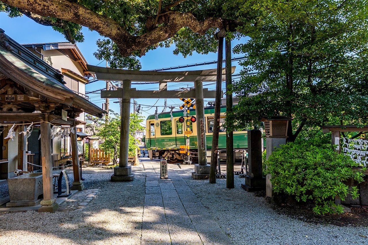 Un tren de la Enoden pasa tras el torī del santuario Goryō. (© Benjamin Parks)