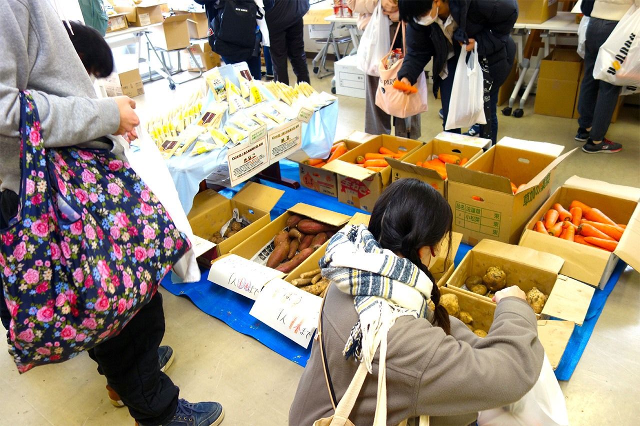 Una joven se lleva patatas suministradas por agricultores de la zona en un reparto para ayudar a los estudiantes organizado en la ciudad de Sagamihara. (Fotografía del autor)