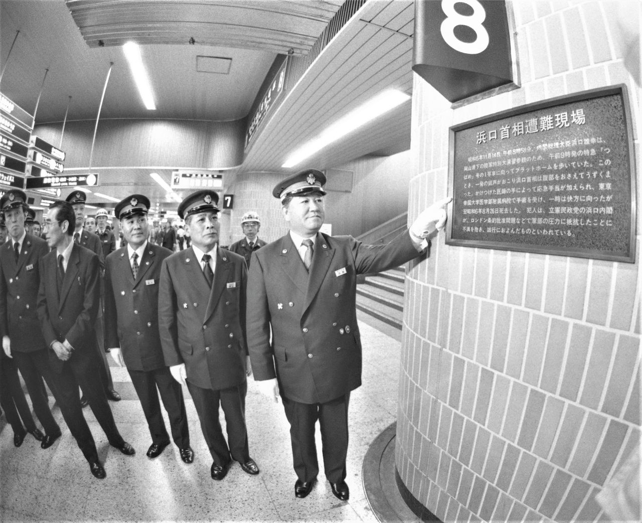Empleados del ferrocarril señalan la placa que marca el lugar en el que fue tiroteado el primer ministro Hamaguchi Osachi en 1930. Actualmente, queda en el subterráneo situado entre las líneas 9 y 10. (Jiji Press)
