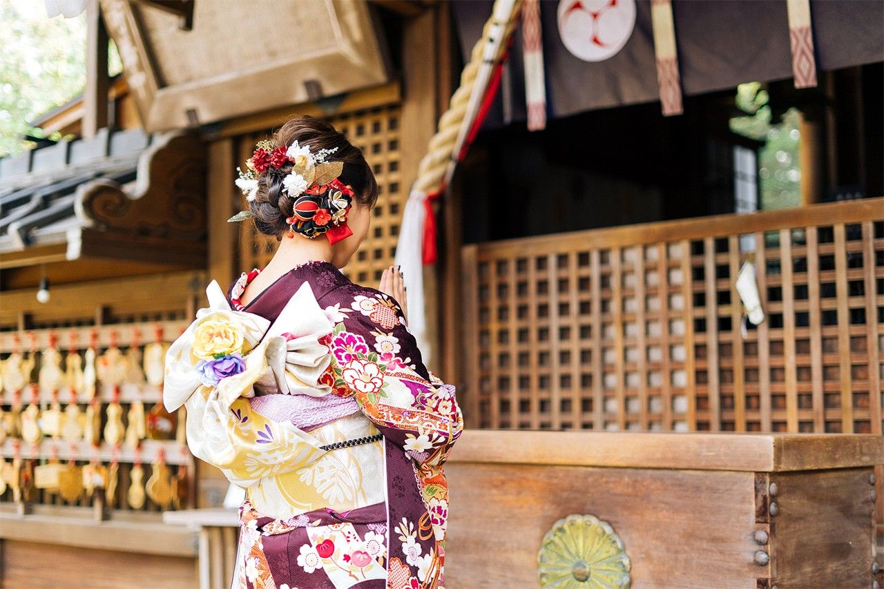 Una mujer reza en un santuario sintoísta con motivo de la primera visita del año o hatsumōde. (PIXTA)