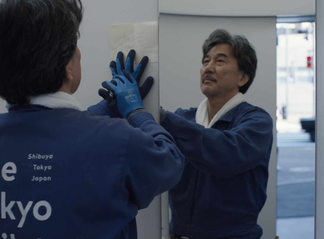 Hirayama (Yakusho Kōji) se dedica en silencio a su trabajo limpiando servicios. ©2023 Master Mind Ltd.