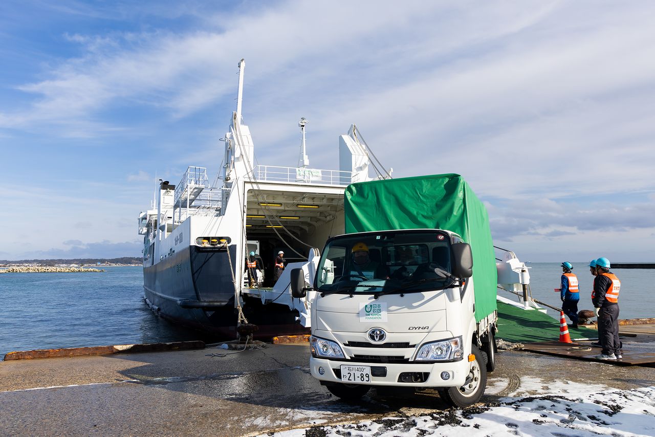 Los camiones van saliendo del ferri a uno de los muelles del puerto de Īda. El sistema Ro-Ro permite hacer llegar los materiales de ayuda con gran rapidez.