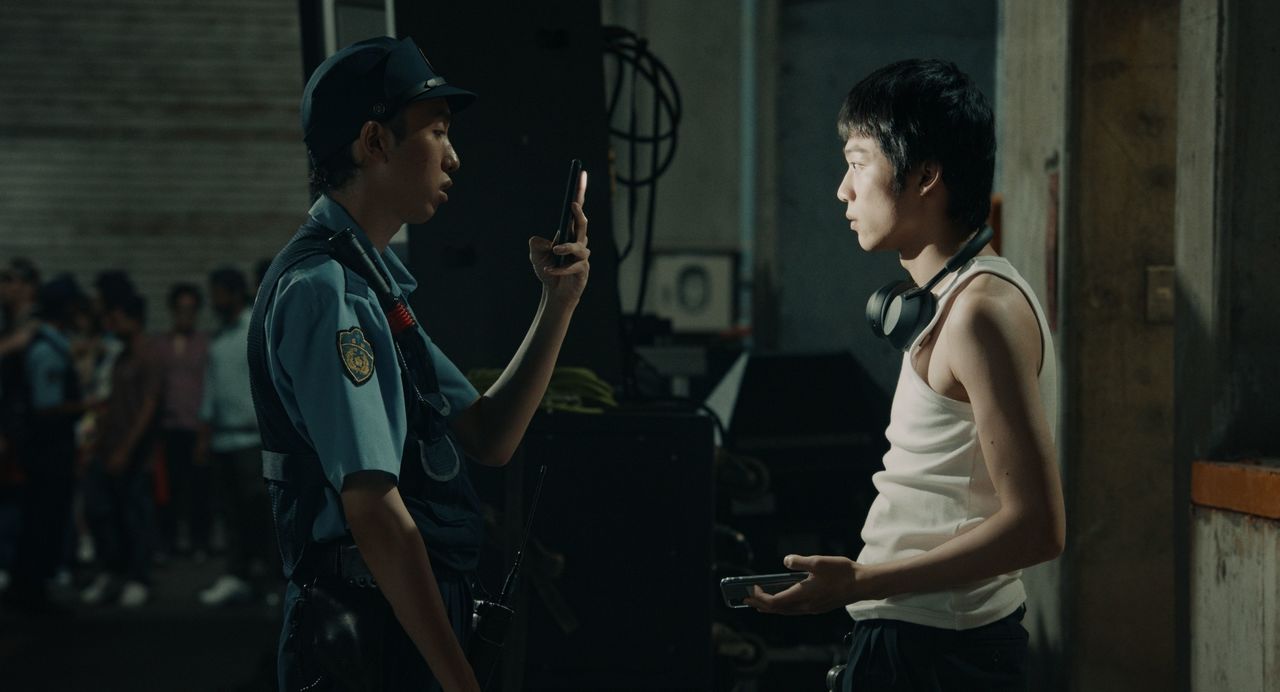 La policía interviene en un concierto de DJs en un club y registra las pertenencias. El terminal del agente revela al momento la identidad. © 2024 Music Research Club LLC