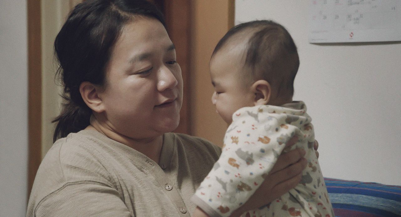 Yoshiki, el hijo menor, en brazos de Aika. Al final de la película ya camina. (© 2024 Takeshi Fukunaga/AINU PURI Production Committee)