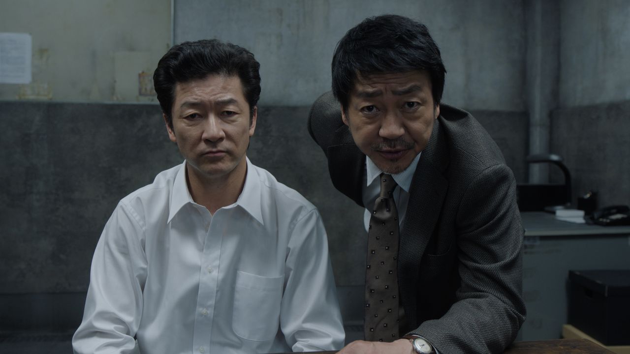 Los detectives Inoue (Asano Tadanobu, izquierda) y Fukuda (Ōmori Nao, derecha) proponen un trato a Nezumi para que colabore en una difícil investigación. © 2025 Amazon Content Services LLC or its Affiliates.