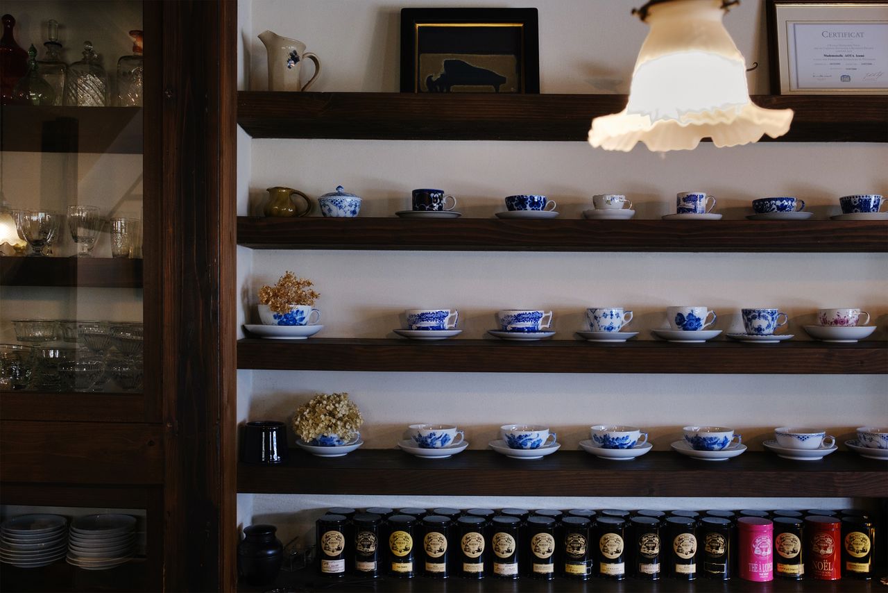 Tazas de té y latas de té negro en una estantería detrás de la barra.