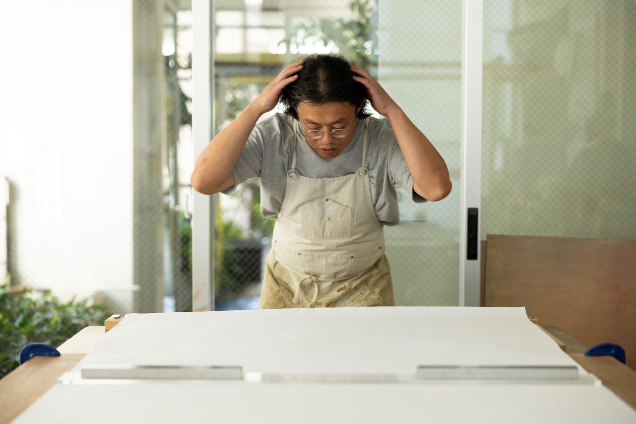 Tocarse el cabello antes de hacer el estampado hace que las manos se deslicen mejor en el papel. Es un truco que Takasugi aprendió de los viejos artesanos.