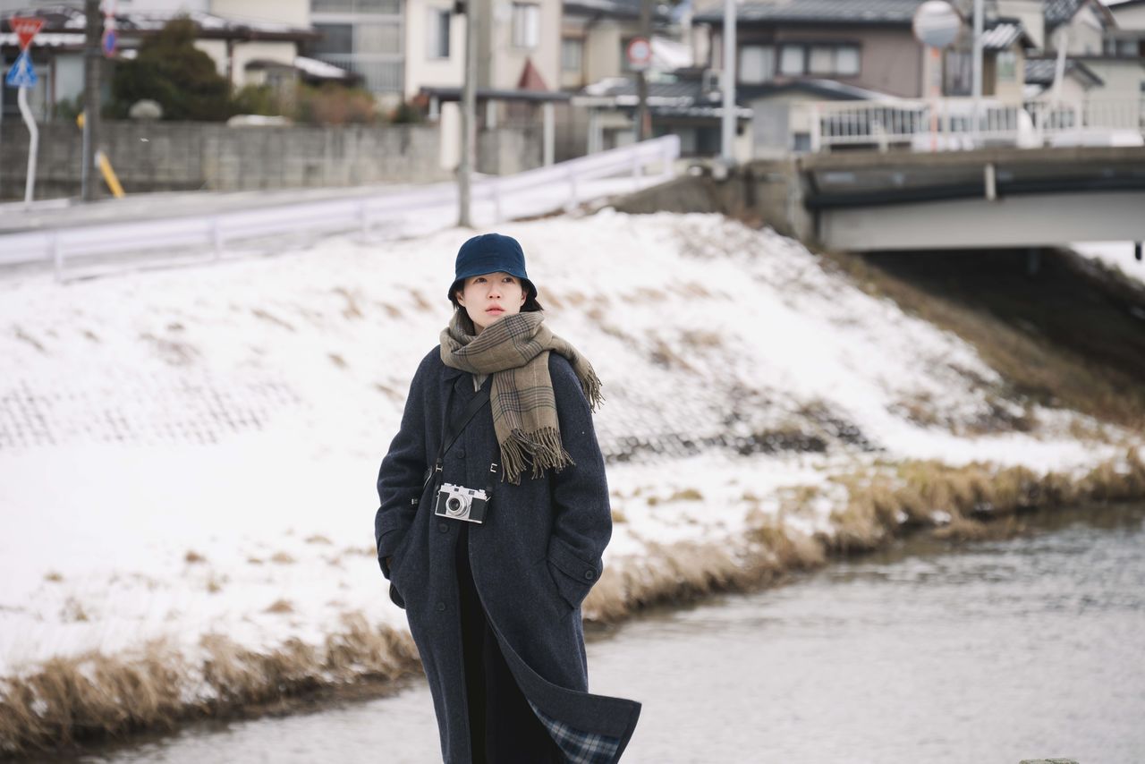 Fotograma de Tabi to hibi. Lee (Shim Eun-kyung), una guionista, parte de viaje hacia una ciudad cubierta de nieve. (© 2025 Comité de Producción de Tabi to hibi)
