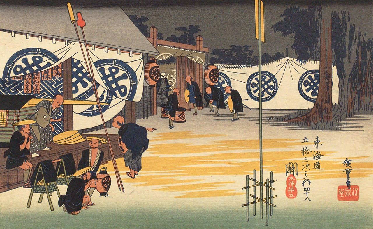 “Seki, honjin hayadachi”, grabado de la serie Tōkaidō gojūsan-tsugi, de Utagawa Hiroshige. En el edificio de la izquierda, bajo las cortinas se ven las tablas sekifuda y un palanquín. Contrariamente a lo que sería de esperar, en las tablas colgantes no aparece el nombre del daimio, sino publicidad de algún cosmético. Los símbolos que adornan el cortinaje tampoco son escudos nobiliarios de ningún daimio, sino una caprichosa combinación de ‘Tanaka’, apellido de la familia paterna de Hiroshige, y de una rueda de carro de bueyes. La escena es una buena muestra del humor del famoso grabador. (Colección de la Biblioteca Nacional de la Dieta) 