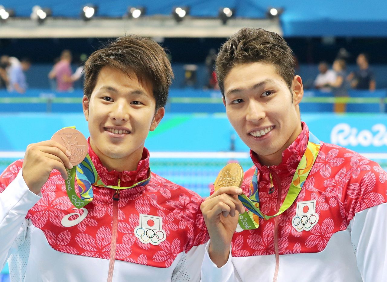 Hagino Kōsuke (derecha) muestra a cámara su medalla de oro junto a Seto, quien hace lo propio con la de bronce, en el podio de las pruebas de combinado individual masculino de 400 metros de los Juegos Olímpicos de Río. (6 de agosto de 2016, Río de Janeiro, Brasil – Jiji Press)