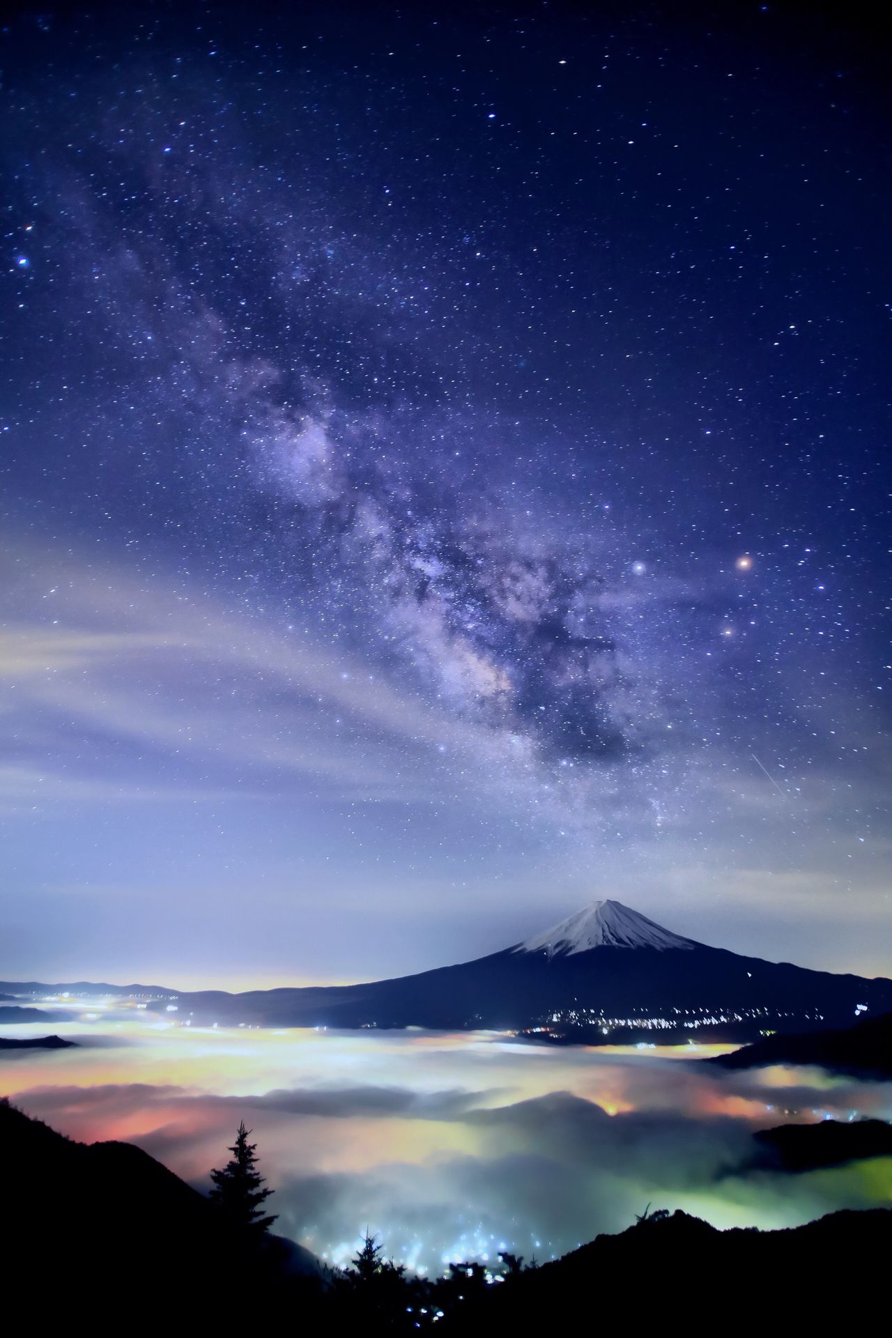 Otro de los elementos más aplaudidos de las fotografías del señor Hashimuki es la belleza de sus cielos estrellados. El monte Fuji y la Vía Láctea hacen una perfecta combinación con el banco de nubes que flota sobre las luces de la ciudad. (imagen de Hashimuki Makoto) 