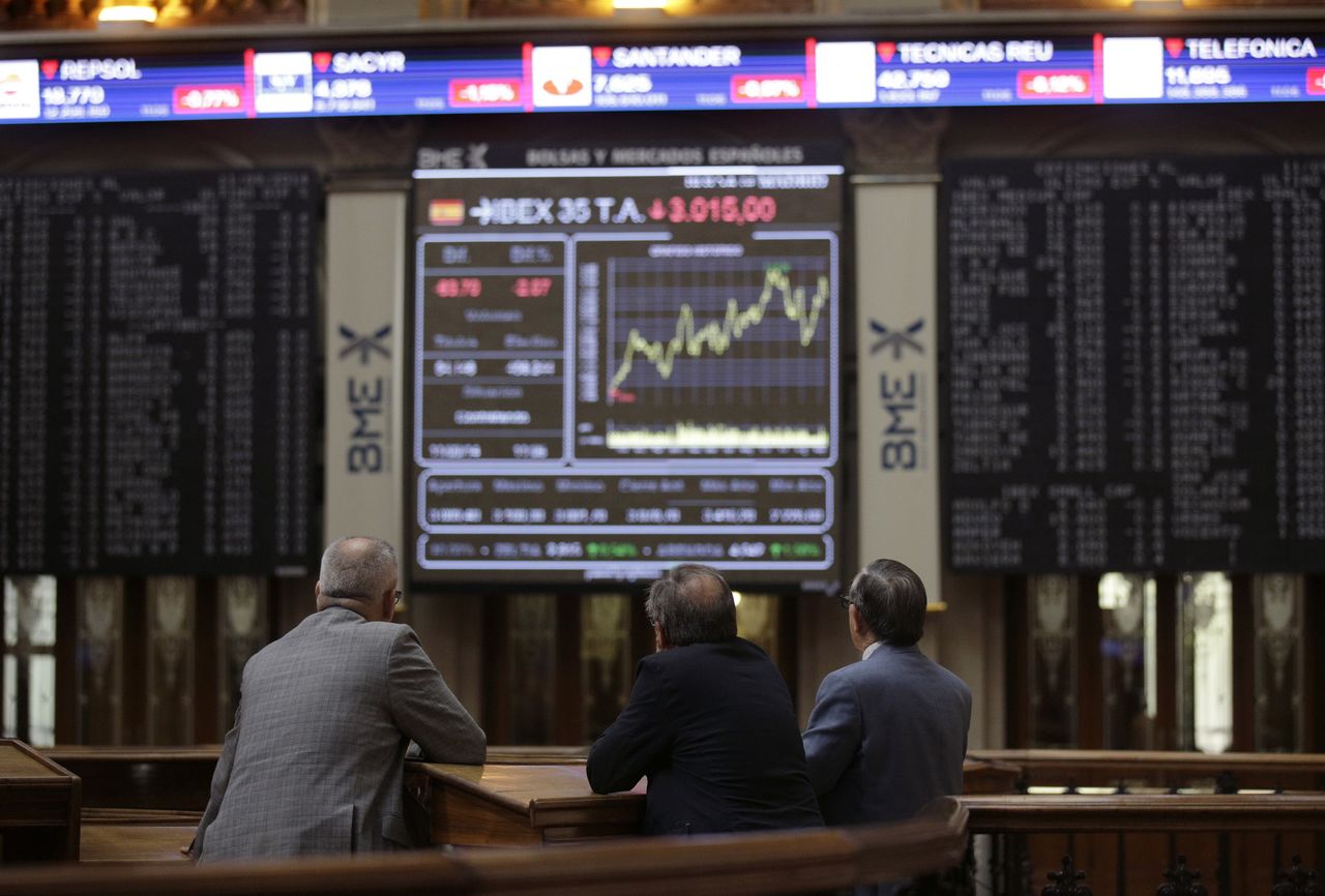 FOTO DE ARCHIVO: Tres hombres observan un panel con datos de cotización en el interior de la Bolsa de Madrid, España, el 11 de septiembre de 2014. REUTERS/Andrea Comas