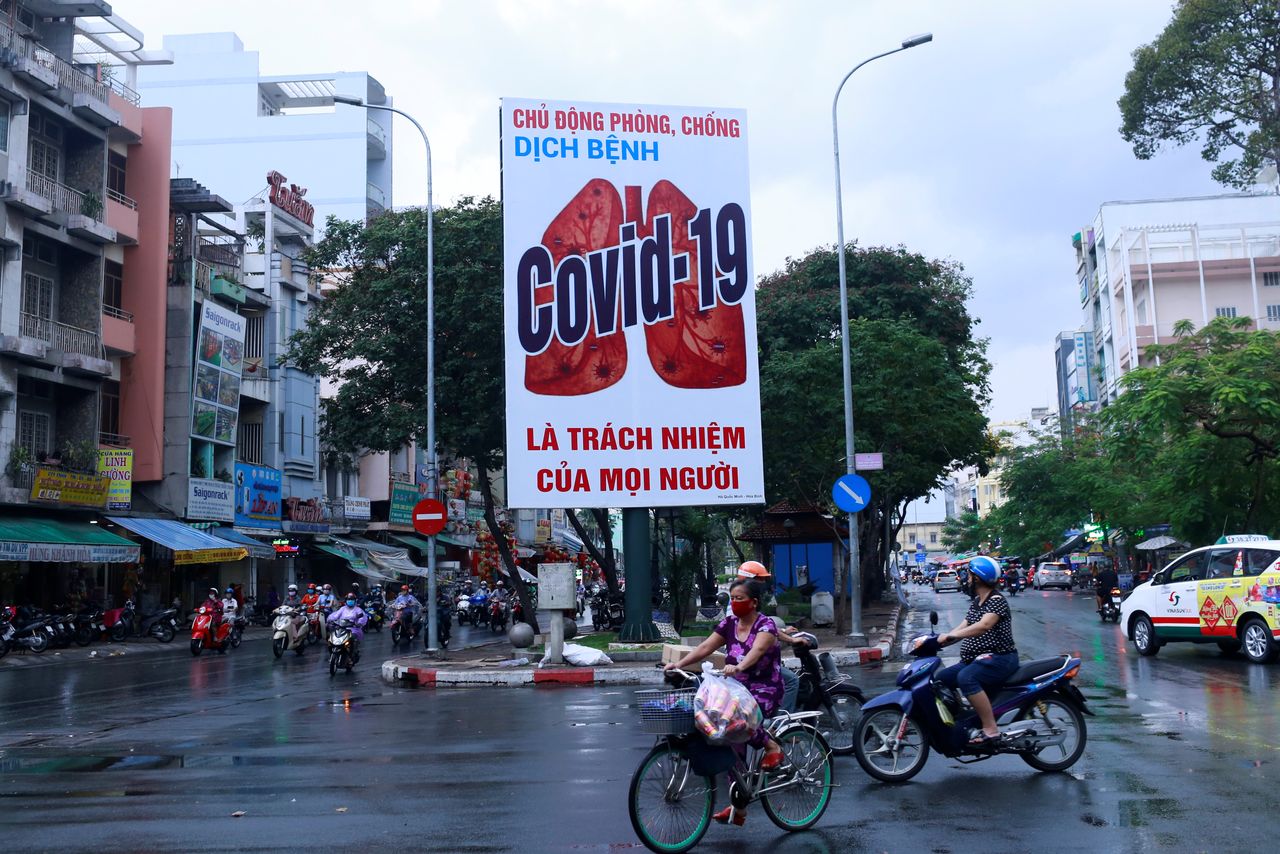 FOTO DE ARCHIVO: Dos motociclistas pasan frente a un cartel informativo sobre la COVID-19 en Ho Chi Minh, Vietnam, el 25 de abril de 2020. REUTERS/Yen Duong