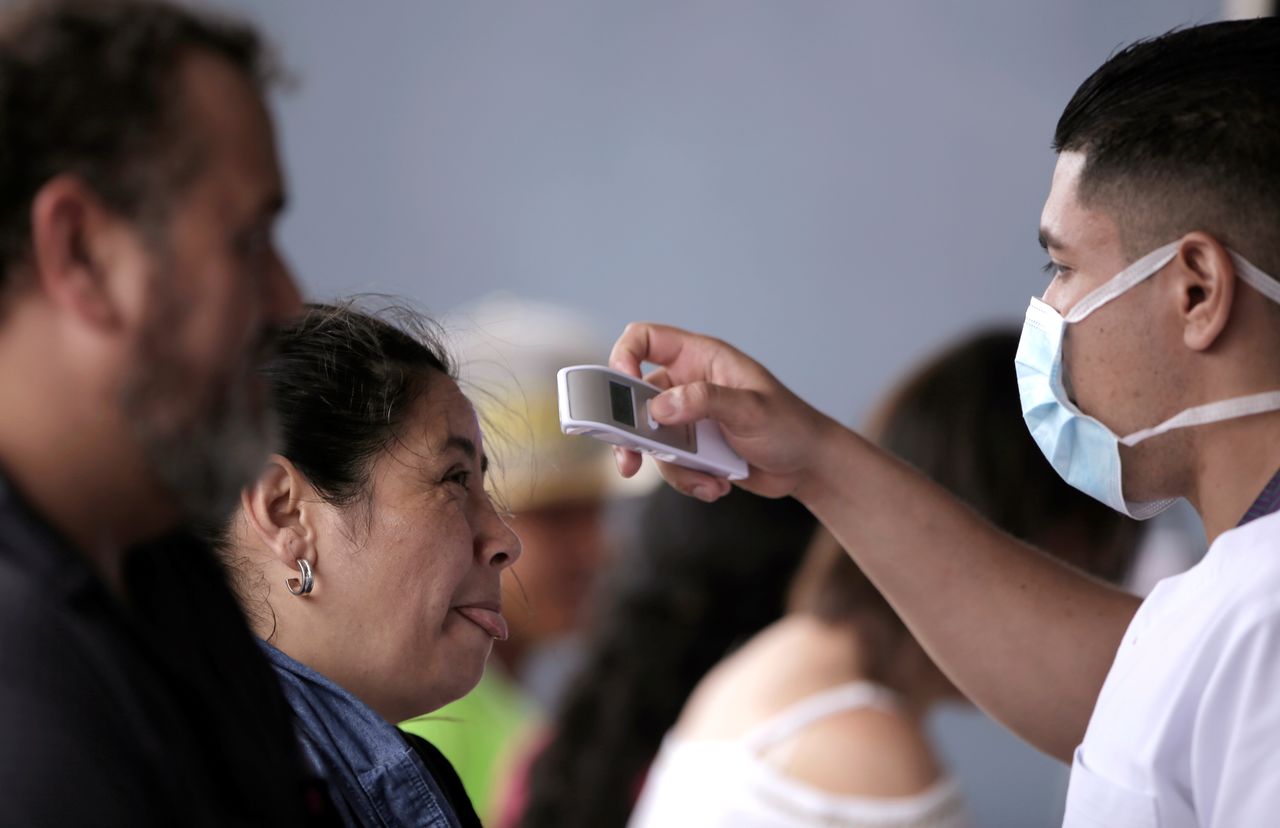 FOTO DE ARCHIVO: Un trabajador sanitario público toma la temperatura a una mujer en San José, Costa Rica, el 12 de marzo de 2020. REUTERS/Juan Carlos Ulate