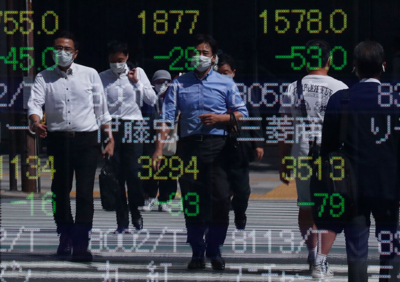 Varios transeúntes se ven reflejados en una pantalla electrónica con los precios de la bolsa al exterior de una correduría en Tokio, Japón. 29 septiembre 2021. REUTERS/Issei Kato
