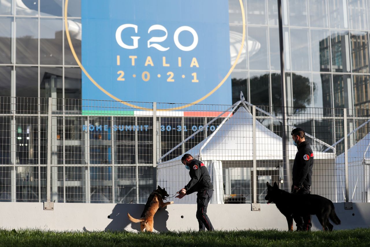 Dos agentes de los Carabinieri italianos y varios perros inspeccionan un área en busca de explosivos en el exterior del centro de convenciones "La Nuvola" (La Nube) antes de la cumbre del G20 que se celebrará en Roma, Italia, el 27 de octubre de 2021. REUTERS/Yara Nardi