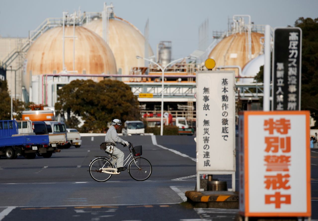 FILE PHOTO: A worker riding a bicycle passes the Fuji Oil Co.