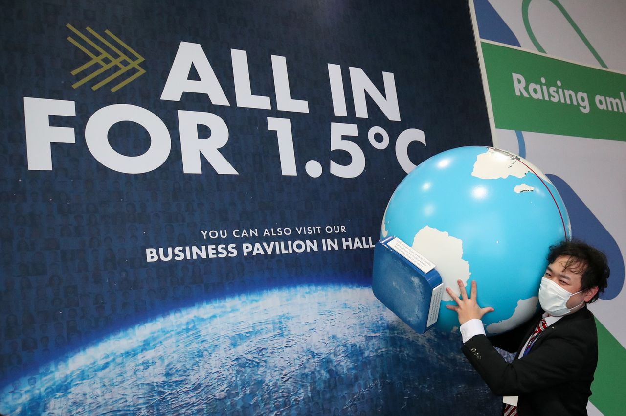 Una persona lleva un modelo de globo terráqueo durante la Conferencia de las Naciones Unidas sobre el Cambio Climático (COP26) en Glasgow, Escocia, Gran Bretaña. 8 de noviembre de 2021. REUTERS/Yves Herman
