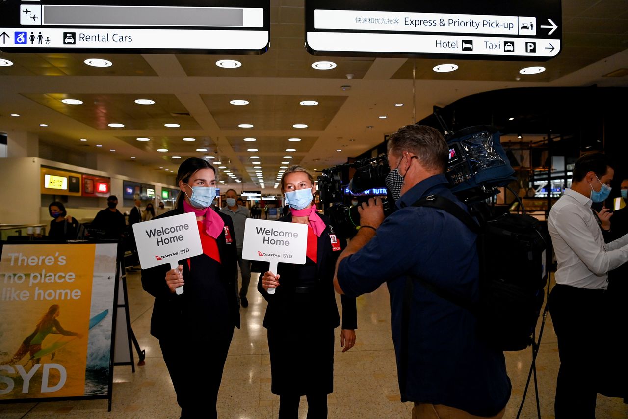 FOTO DE ARCHIVO: El personal del aeropuerto sostiene carteles de bienvenida mientras los primeros viajeros internacionales llegan al aeropuerto de Sídney tras la flexibilización de las restricciones fronterizas por la enfermedad del coronavirus (COVID-19), permitiéndose a los australianos totalmente vacunados entrar en Sídney desde el extranjero sin cuarentena por primera vez desde marzo de 2020, en Sídney, Australia, 1 de noviembre de 2021.  REUTERS/Jaimi Joy