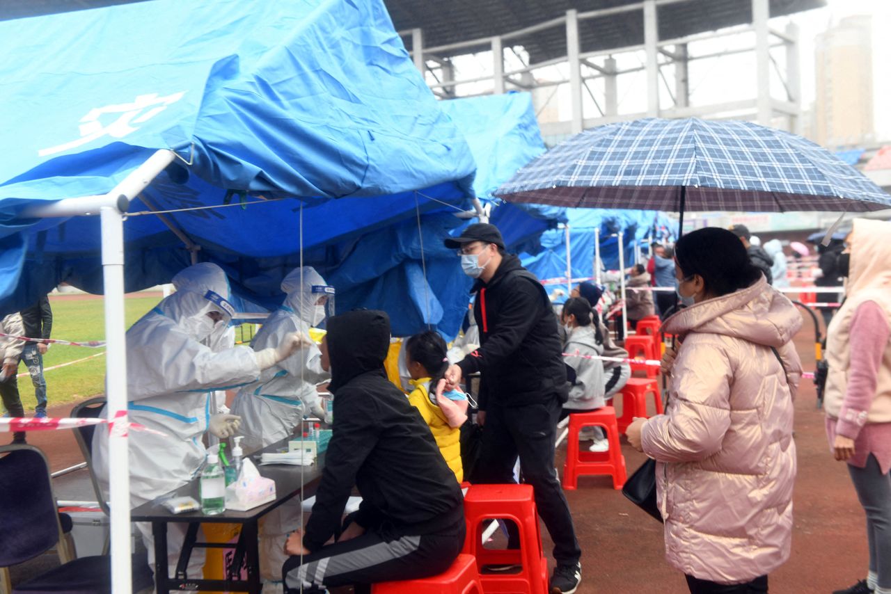 Gente haciendo cola bajo la lluvia en un sitio de pruebas de ácido nucleico para el COVID-19 en Dongxing, una ciudad fronteriza con Vietnam, en la Región Autónoma de Guangxi Zhuang, China, 27 de diciembre de 2021. REUTERS/cnsphoto