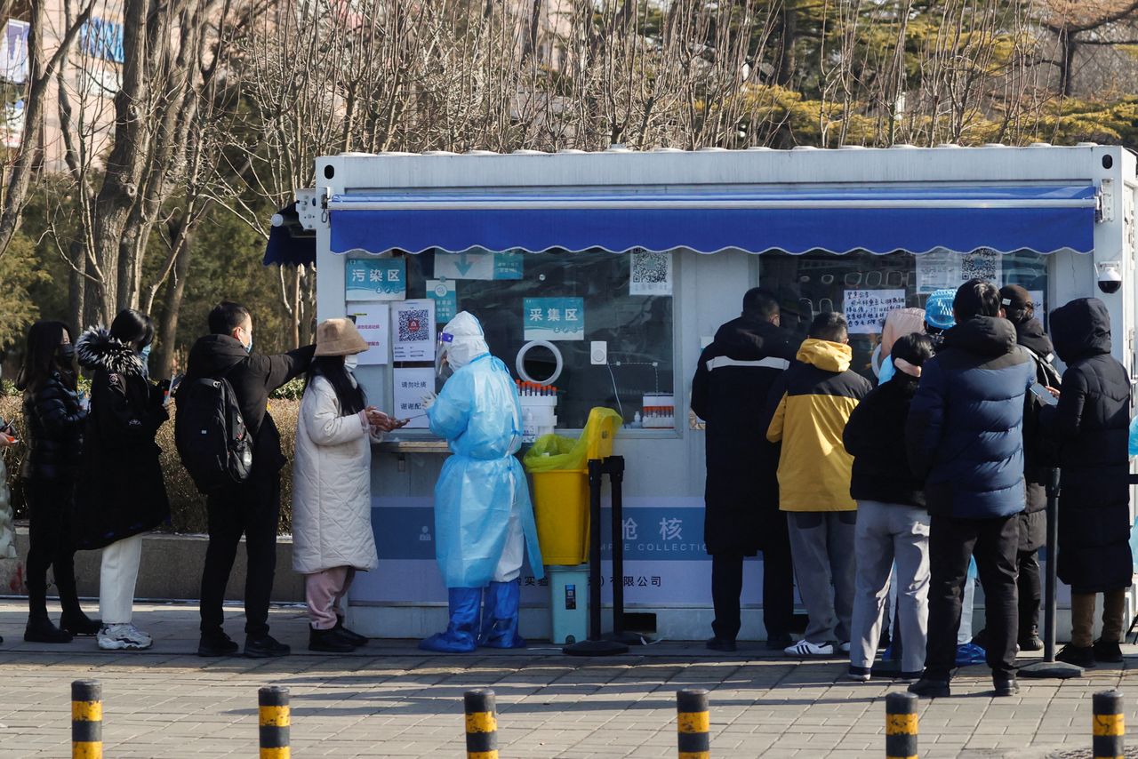 Gente haciendo cola para someterse a una prueba de ácido nucleico en un centro de pruebas temporal situado en un complejo residencial, tras los nuevos casos confirmados de COVID-19, en Pekín, China, 25 de enero de 2022. REUTERS/Tyrone Siu