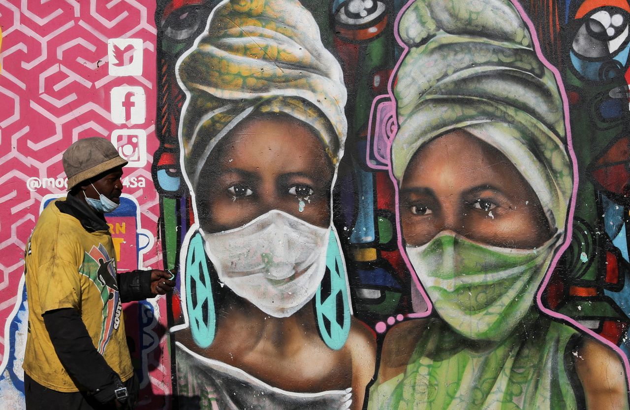 FOTO DE ARCHIVO: Un hombre pasa frente a un mural que representa a dos mujeres con mascarilla en el barrio Kliptown de Soweto, Sudáfrica, el 1 de febrero de 2022. REUTERS/Siphiwe Sibeko