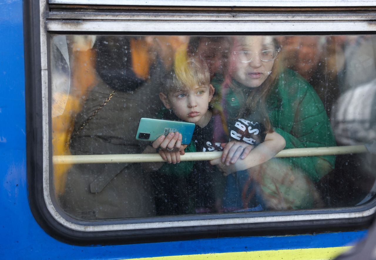 Una mujer y su hijo miran desde un tren de evacuación de Kiev a Leópolis en la estación central de trenes de Kiev, Ucrania. 25 de febrero de 2022. REUTERS/Umit Bektas