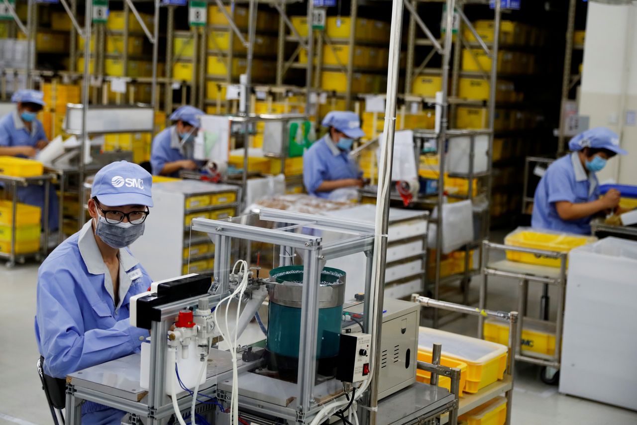 FOTO DE ARCHIVO: Empleados con mascarillas trabajan en una fábrica del fabricante de componentes SMC en Pekín, China, 13 de mayo de 2020. REUTERS/Thomas Peter