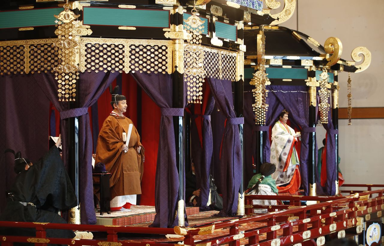 El Emperador Naruhito en pie en el takamikura, una plataforma de ocho toneladas de peso con un recinto con forma octogonal. En el fondo se puede ver a la Emperatriz Masako en el mi-chōdai, una plataforma ceremonial ligeramente más pequeña. (© Jiji)