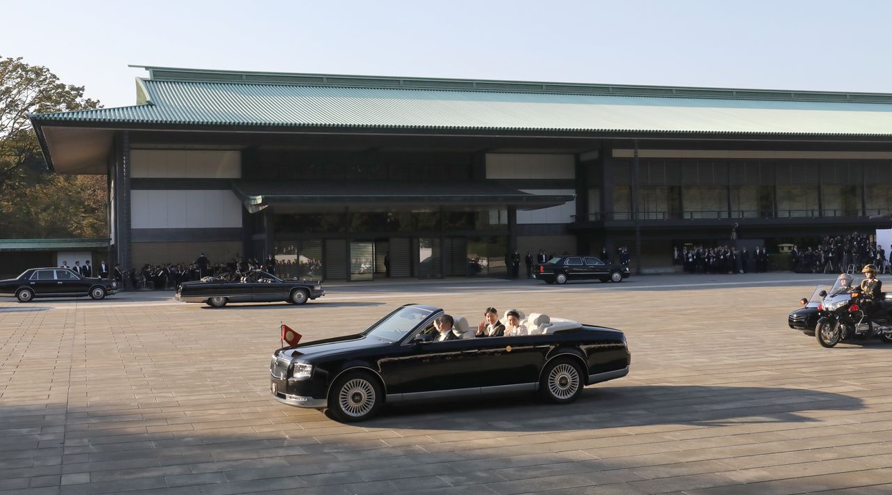 El Emperador y la Emperatriz parten en un vehículo descubierto desde el Palacio Imperial. (Jiji)