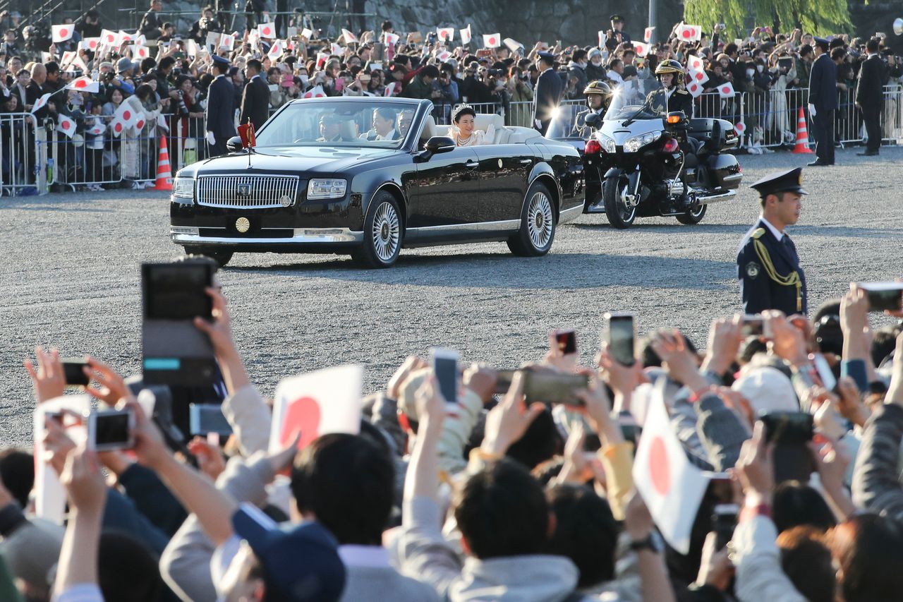 El Emperador y la Emperatriz saludan a los numerosos asistentes que se acercaron para ver el desfile. (Jiji)