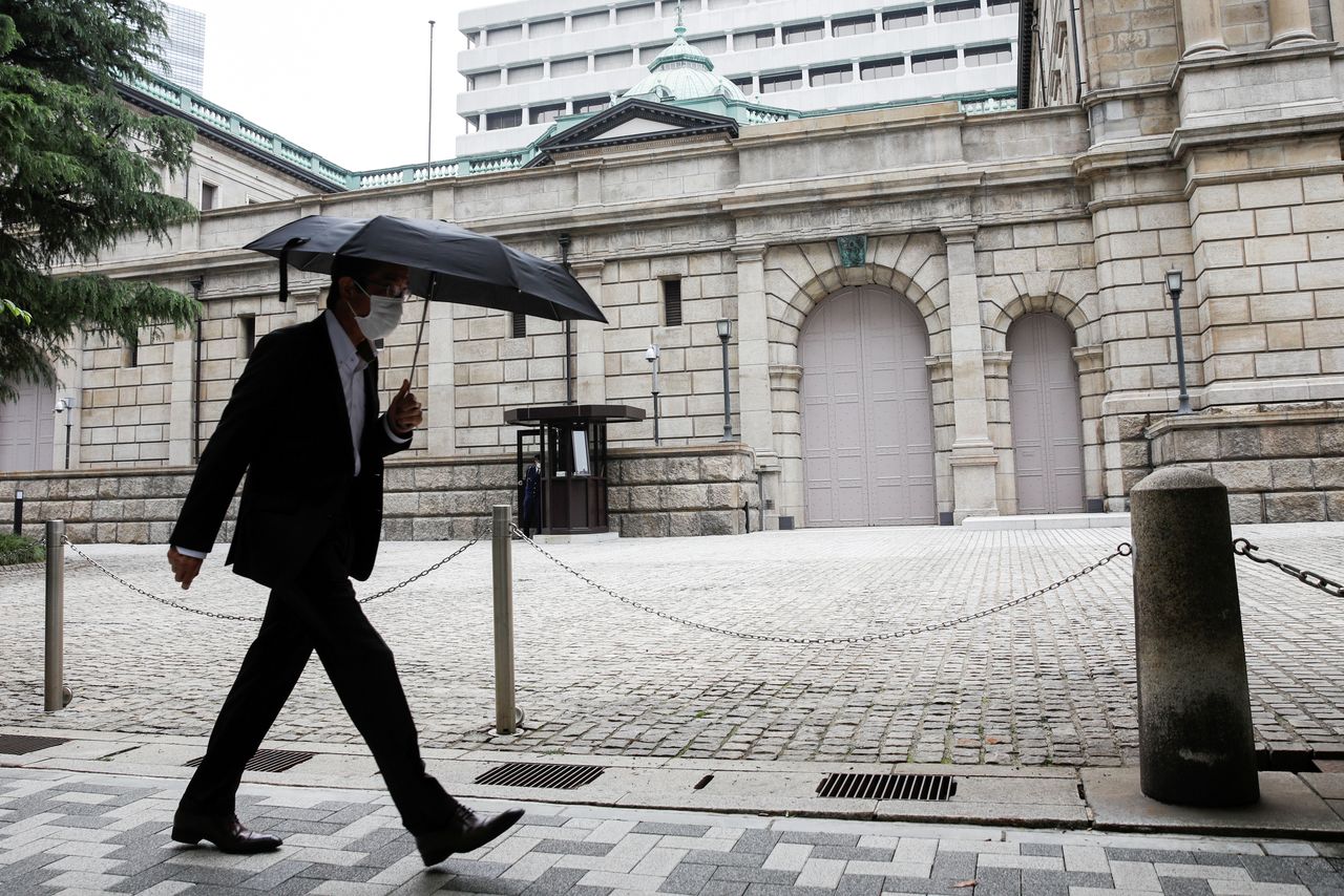 FOTO DE ARCHIVO: Un hombre con paraguas y mascarilla camina frente a la sede del Banco de Japón en Tokio, Japón, el 22 de mayo de 2020. REUTERS/Kim Kyung-Hoon