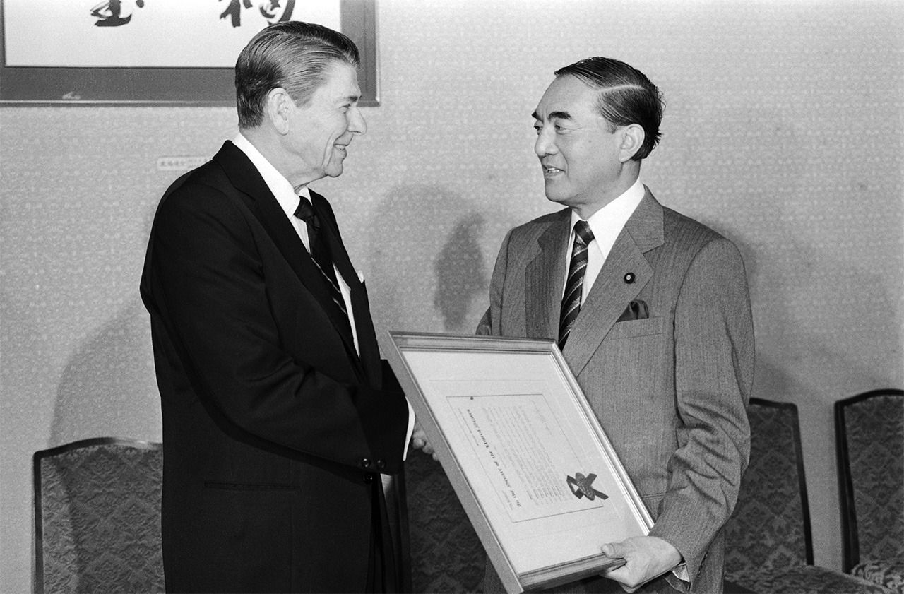 El primer ministro Nakasone Yasuhiro (a la derecha) intercambia unas palabras con el presidente estadounidense Ronald Reagan en Tokio el 11 de noviembre de 1983. (© Jiji)