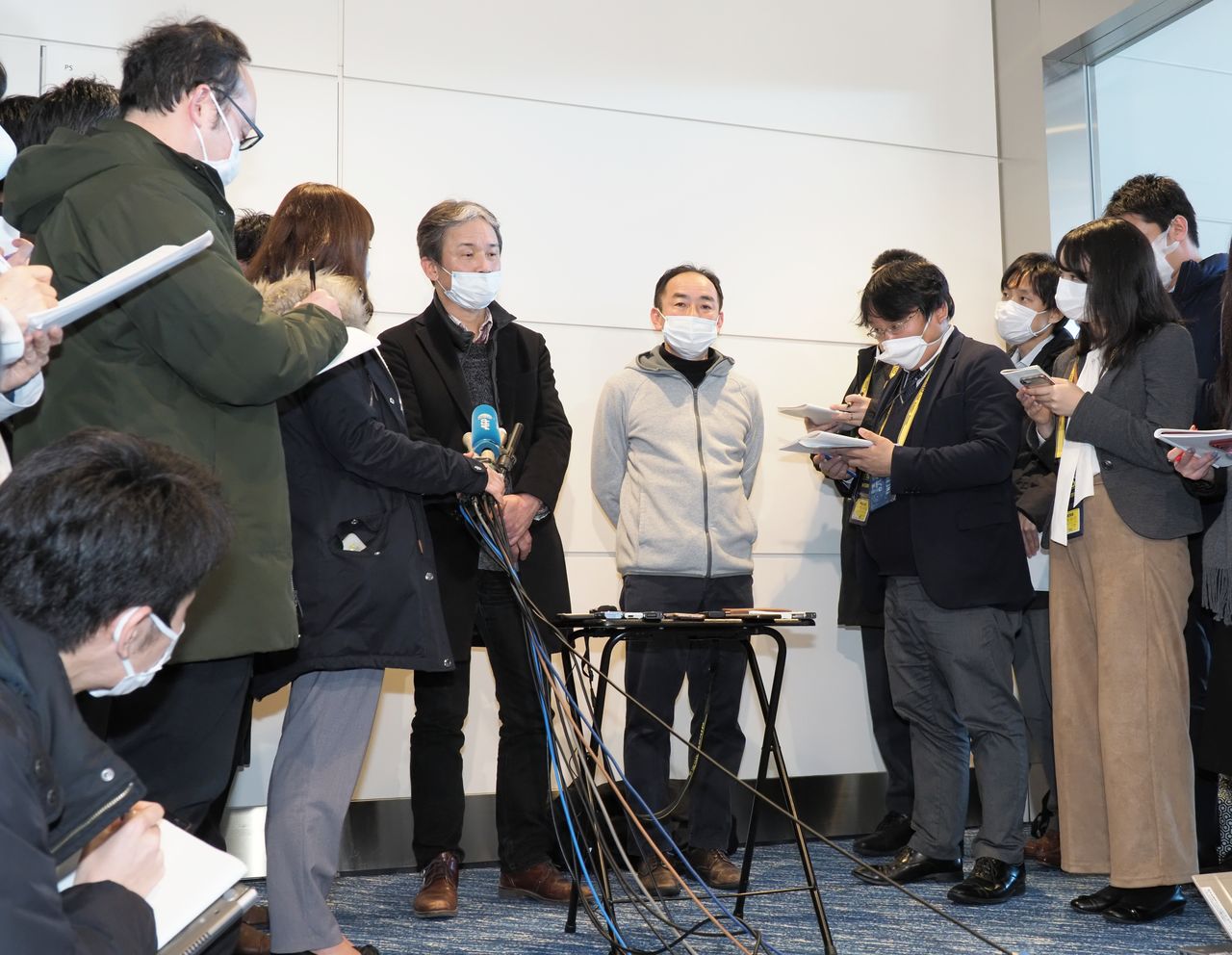 Ciudadanos japoneses repatriados desde Wuhan hablan con miembros de la prensa en el aeropuerto de Haneda el 29 de enero de 2020. (© Jiji)