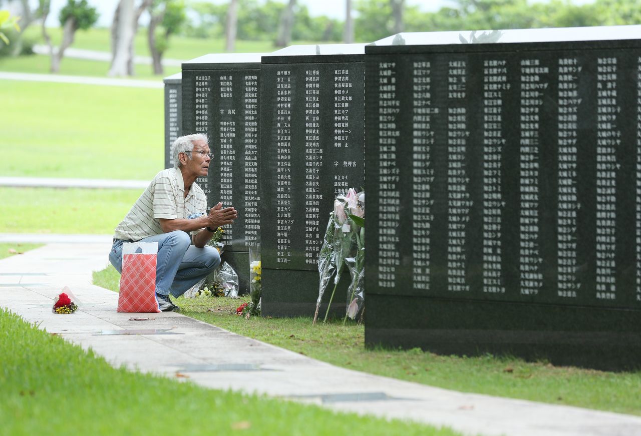Un hombre reza frente al monumento de la Piedra Angular de la Paz en el Parque Conmemorativo de la Paz de Itoman, en Okinawa el 23 de junio de 2020. (© Jiji)