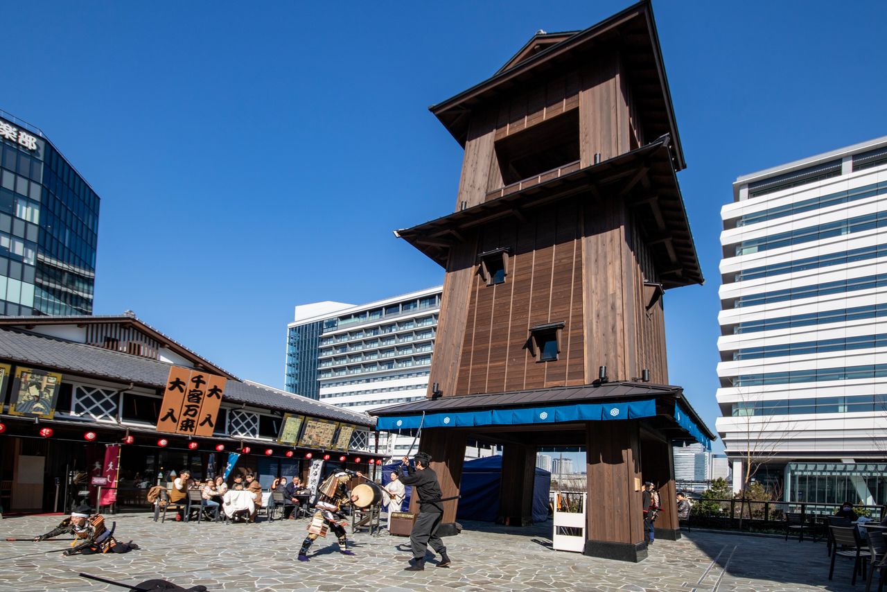 Actores representan una escena de pelea en una plaza frente a la torre de la Campana del Tiempo. Estos espectáculos podrán verse hasta finales de marzo. (© Nippon.com)