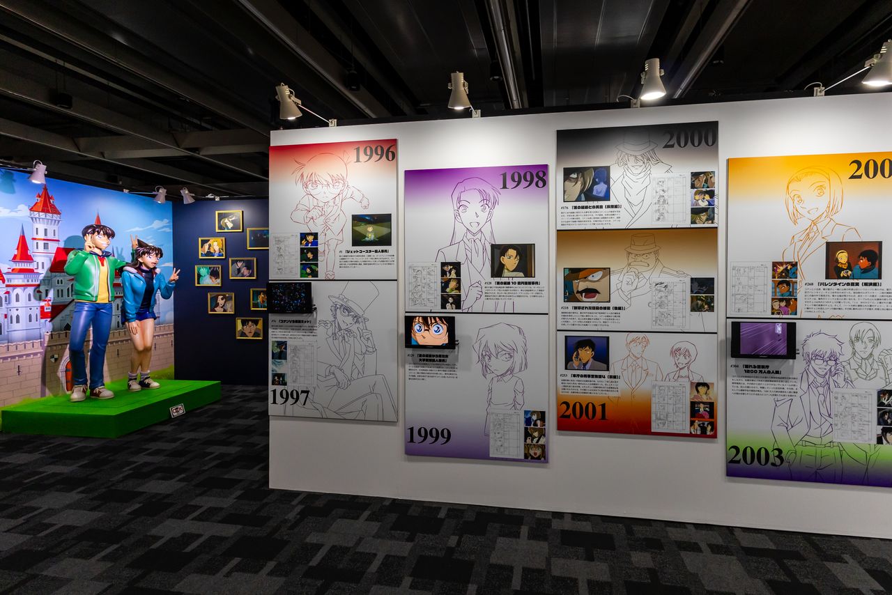 Una hilera de fotografías de escenas famosas y guiones gráficos. También es posible tomarse fotos junto a las figuras de Shin’ichi y la heroína, Mōri Ran. (© Aoyama Gōshō / Shōgakukan, Yomiuri TV, TMS 1996.)