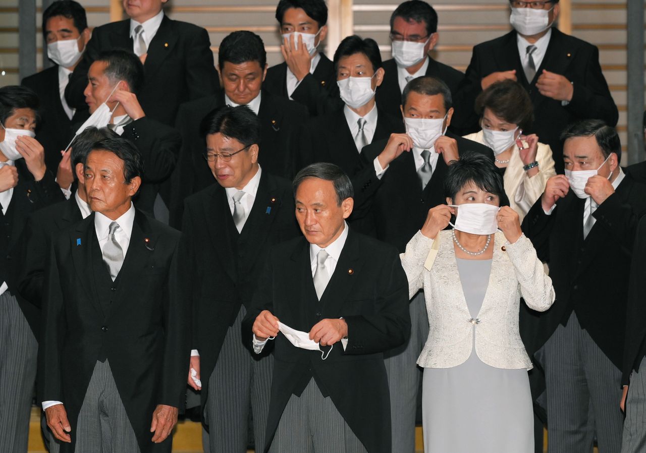 El primer ministro Suga Yoshihide (en el centro) y los miembros de su Gabinete se ponen la mascarilla tras tomarse las fotografías conmemorativas después de una ceremonia en el Palacio Imperial el 16 de septiembre de 2020. (© Jiji)