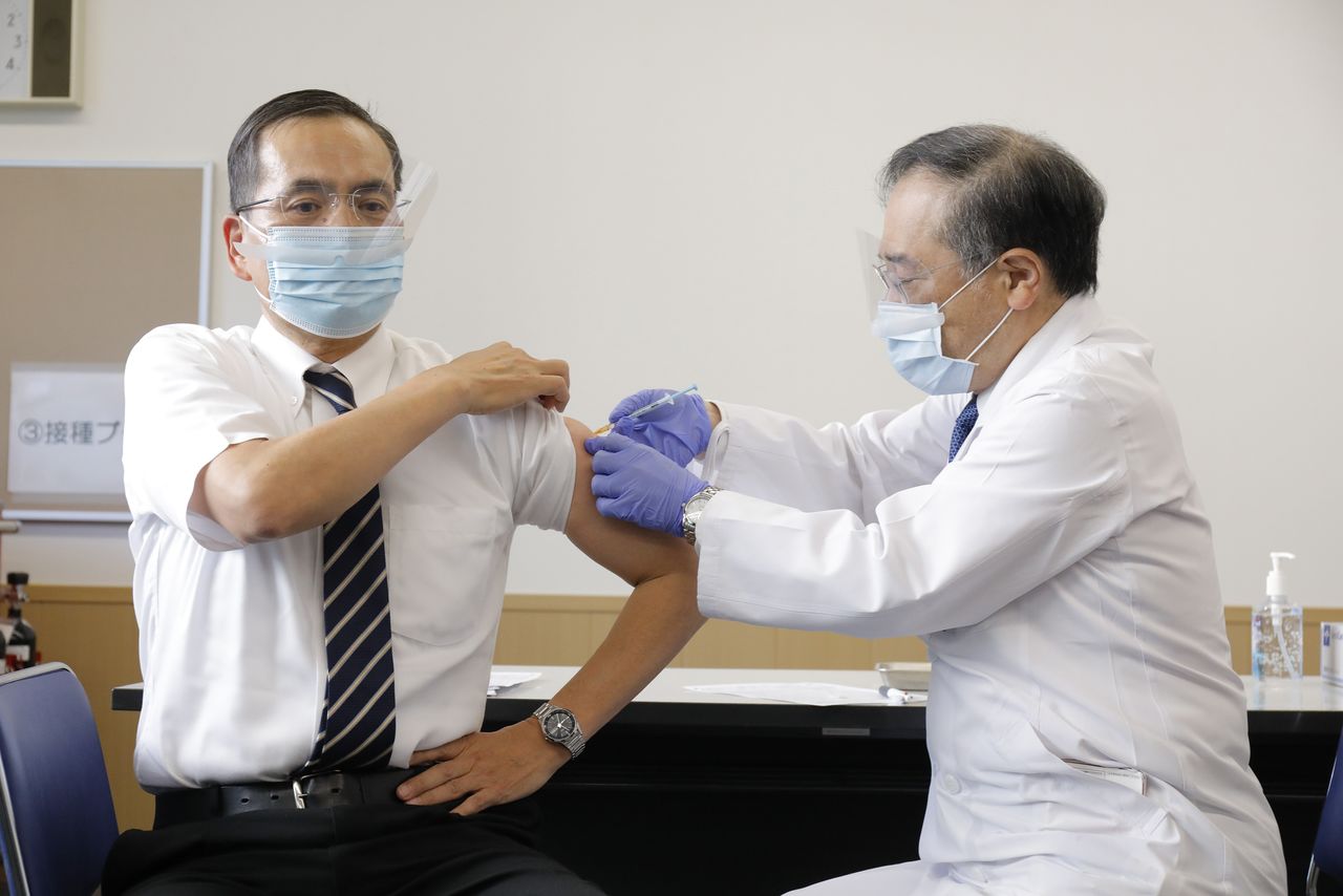 Araki Kazuhiro (a la izquierda), presidente del Centro Médico de Tokio de la Organización Nacional de Hospitales, recibe la primera vacuna contra la COVID-19 el 17 de febrero de 2021. (© Jiji)