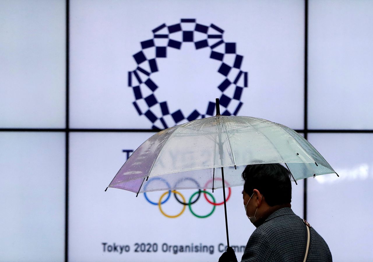 FOTO DE ARCHIVO: Un hombre con una máscara protectora pasa frente a una pantalla que muestra el logotipo de los Juegos Olímpicos de Tokio 2020 que se pospusieron hasta 2021 debido al brote de la enfermedad del coronavirus (COVID-19), en Tokio, Japón, el 23 de enero. 2021.REUTERS/Issei Kato/File Photo
