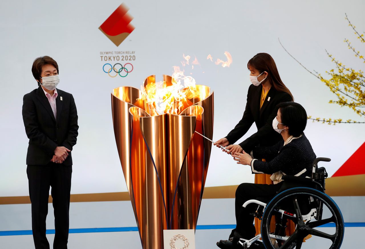La presidenta de Tokio 2020 Hashimoto Seiko observa cómo la actriz Ishihara Satomi y el deportista paralímpico Taguchi Aki encienden el pebetero en el primer día del relevo de la antorcha de los Juegos de Tokio 2020 en Naraha, en la prefectura de Fukushima, el 25 de marzo de 2021 en Japón. REUTERS/Kim Kyung-Hoon/Pool