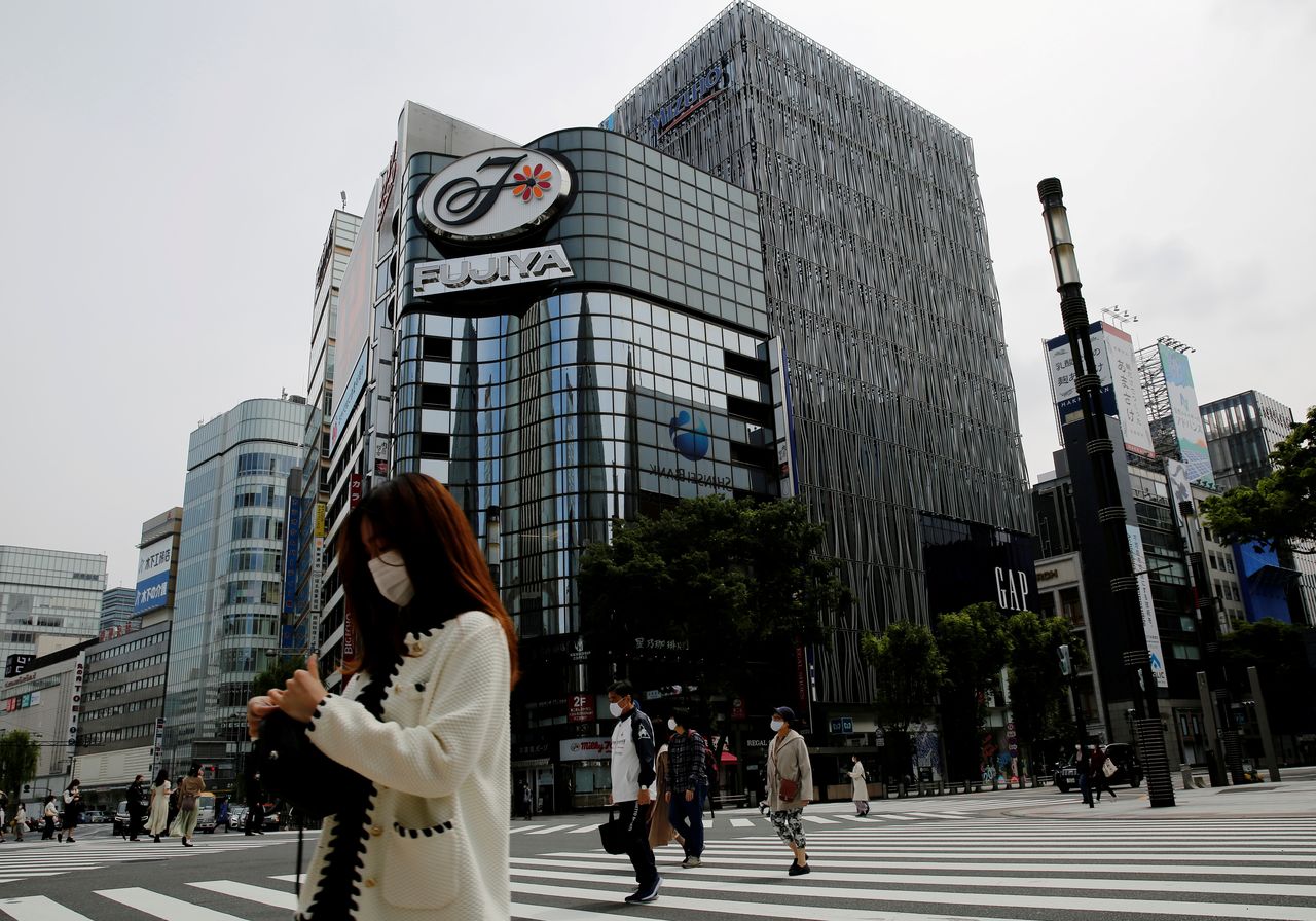 Peatones con mascarilla en un distrito comercial, menos concurrido de lo habitual en el primer día del tercer estado de emergencia del país, durante la epidemia de coronavirus (COVID-19), en Tokio, Japón, 25 de abril de 2021. REUTERS/Kim Kyung-Hoon