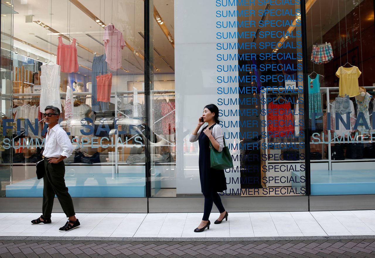 FOTO DE ARCHIVO: Dos personas pasan frente al escaparate de una tienda en un distrito comercial de Tokio, Japón, el 20 de julio de 2018. REUTERS/Kim Kyung-Hoon