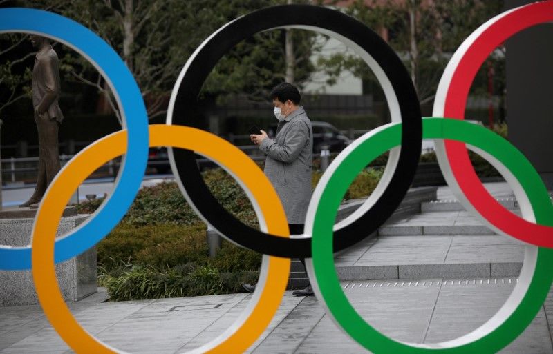 FOTO DE ARCHIVO: Un hombre mira su teléfono móvil junto a los anillos olímpicos frente al Museo Olímpico de Japón en Tokio, Japón, el 4 de marzo de 2020. REUTERS/Stoyan Nenov