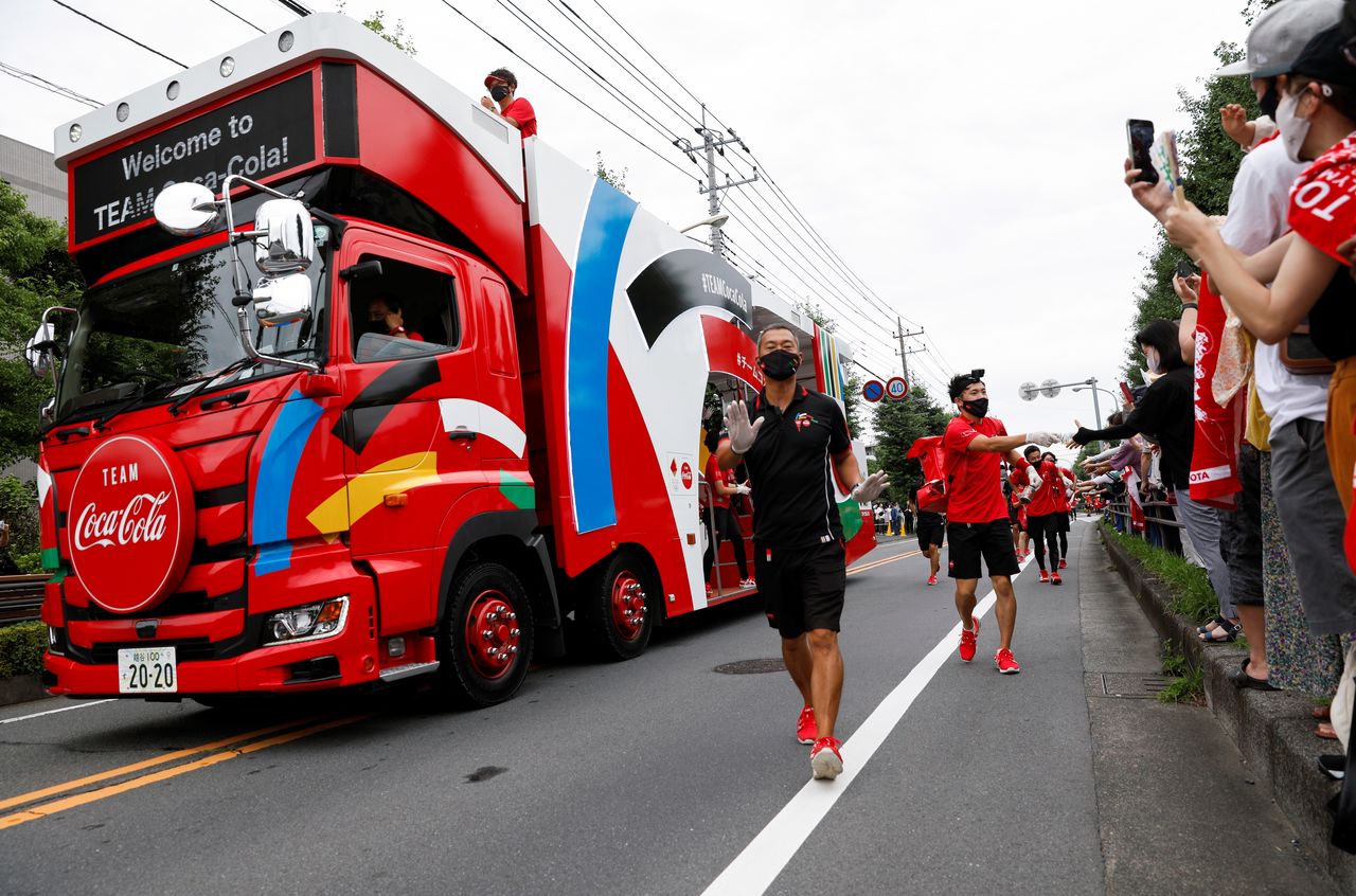 Un camión y personal de un patrocinador despejan el camino antes del paso del corredor que porta la Antorcha Olímpica de Tokio 2020 durante su relevo en la prefectura de Saitama, en medio de la pandemia de COVID-19, en Wako, Japón. 6 de julio, 2021. REUTERS/Androniki Christodoulou