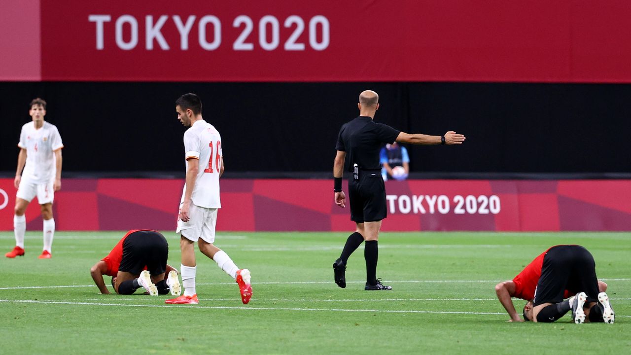 Juegos Olímpicos de Tokio 2020 - Fútbol - Masculino - Grupo C - Egipto contra España - Sapporo Dome, Sapporo, Japón - 22 de julio de 2021. Los jugadores de Egipto rezan al final del partido mientras Pedri, de España, parece abatido REUTERS/Kim Hong-Ji