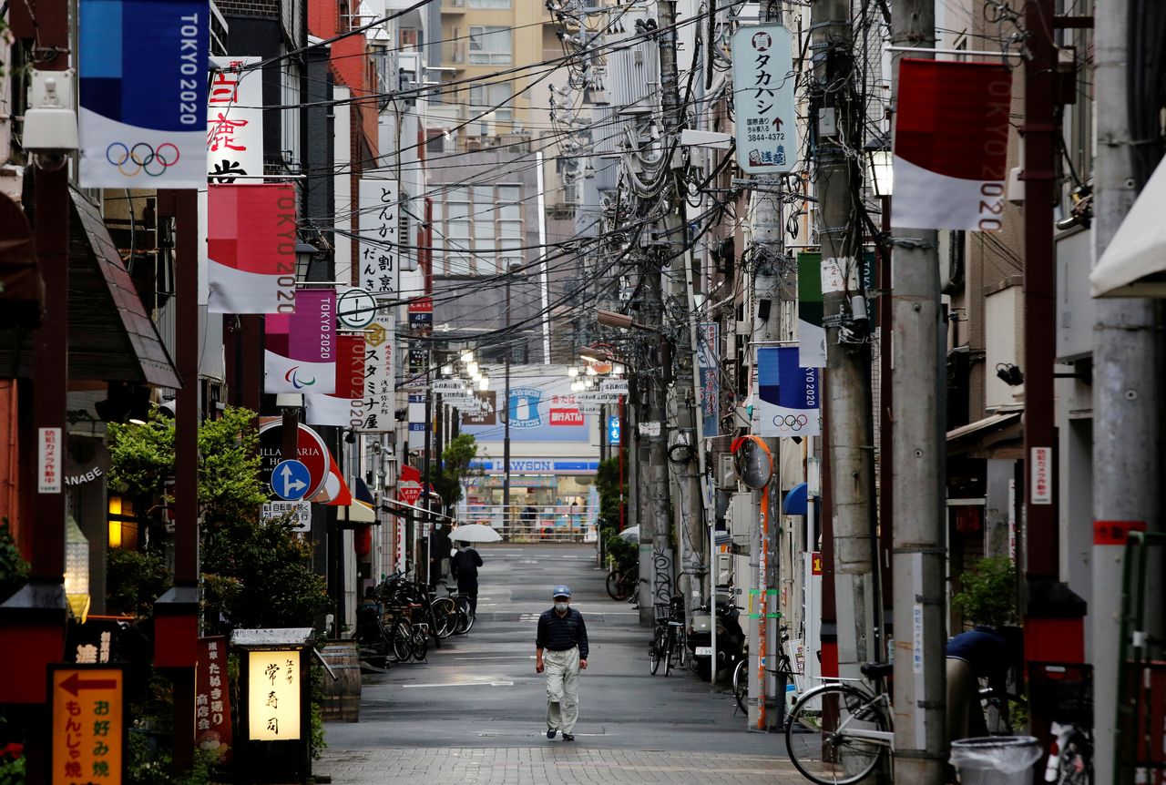 FOTO DE ARCHIVO: Un hombre camina en una calle comercial local decorada con banderas de los Juegos Olímpicos de Tokio 2020, en Tokio, Japón, el 7 de mayo de 2021. REUTERS/Kim Kyung-Hoon
