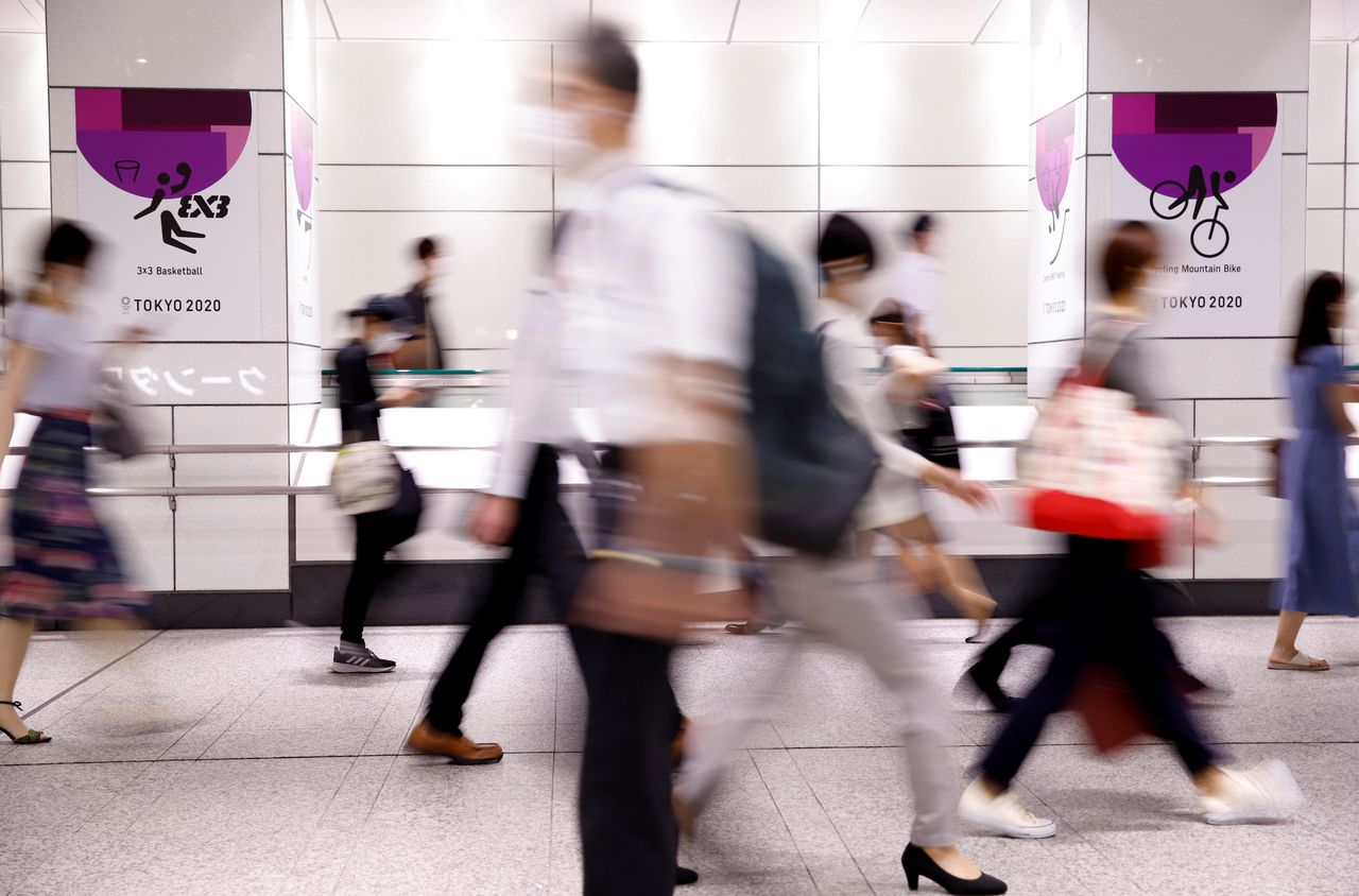 FOTO DE ARCHIVO: Gente pasa frente a anuncios de los Juegos Olímpicos de Tokio 2020 en un paso subterráneo de la estación de Shinjuku en la hora pico de la mañana, en medio del estado de emergencia, en Tokio, Japón, el 26 de julio de 2021. REUTERS/Androniki Christodoulou/File Photo