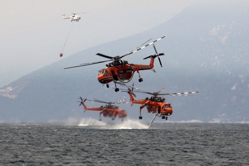 FOTO DE ARCHIVO: Varios helicópteros cargan agua en la playa del pueblo de Pefki, en la isla de Evia, Grecia, el 10 de agosto de 2021. REUTERS/Nicolas Economou